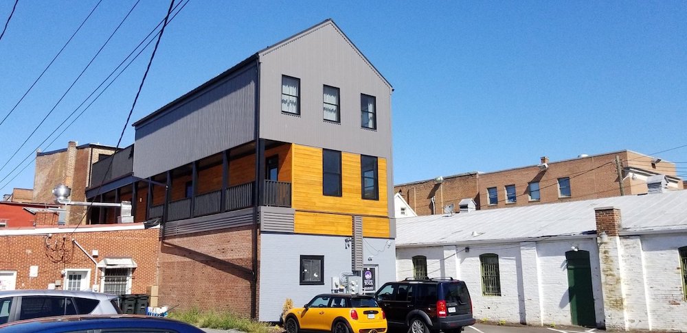 Historic downtown brick building rehab 'after' picture with modern gray panels and honey wood siding that gives a pop of bright orange color